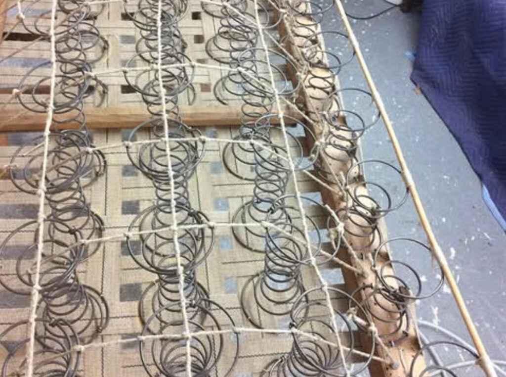 Traditional coil springs being hand-tied during Chesterfield restoration